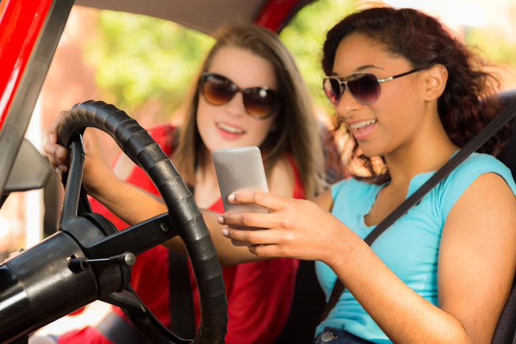 image of girls driving using mobile device