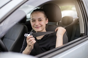 young female driver putting on seatbelt
