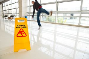 man slipping on wet floor next to wet floor sign